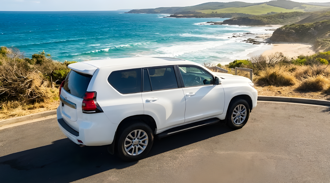 a white rental suv parked in an iconic australian viewpoint by the beach