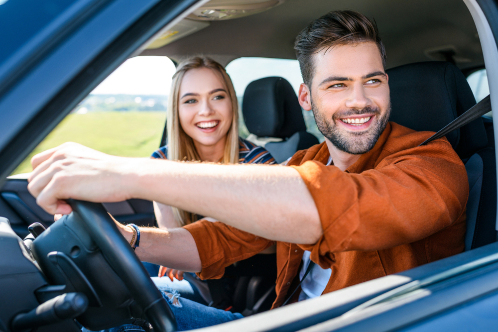 close up shot of smiling young couple sitting in car