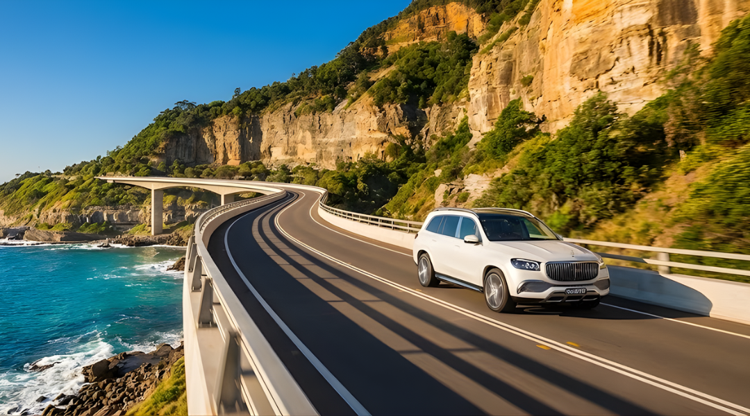 A white SUV driving along the scenic Sea Cliff Bridge south of Sydney on a bright sunny day.