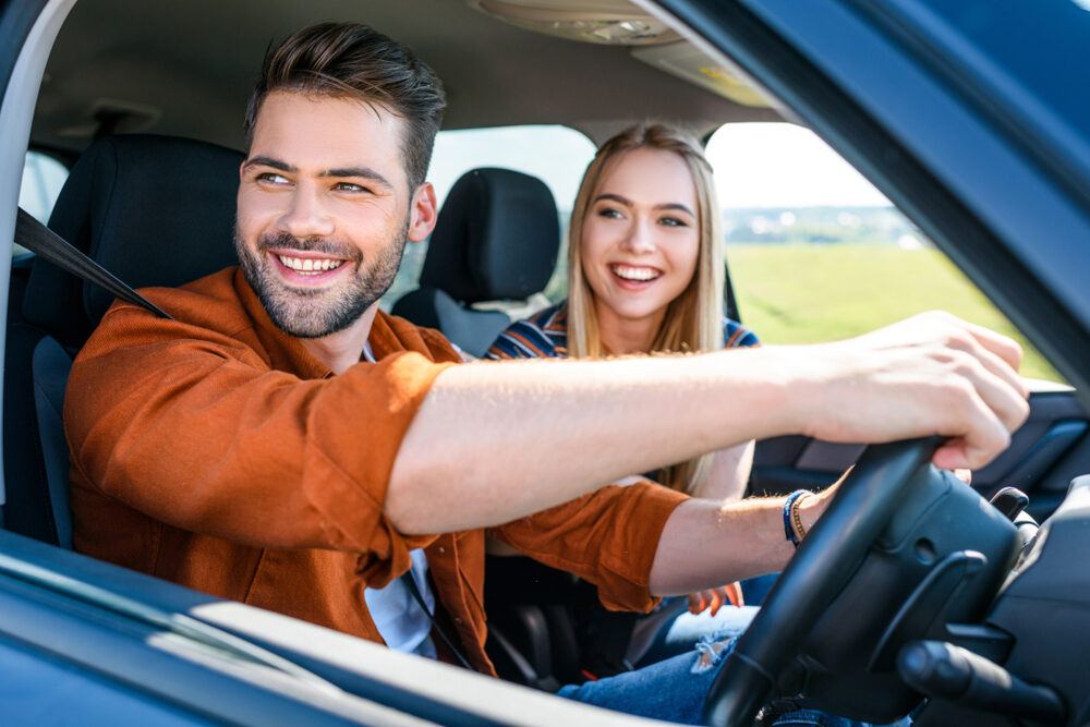 close up shot of smiling young couple sitting in car