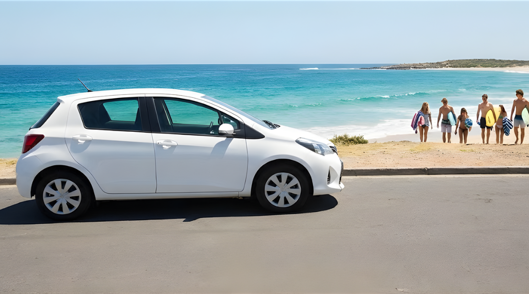 unbranded compact hatchback parked on a coastal road overlooking the ocean. In the background, there is a hint of a beach setting with young adults (students)