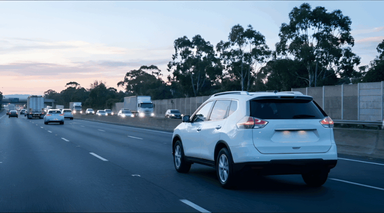SUV driving on a modern multi-lane highway (Australian motorway style). The traffic in the background is moderate but flowing.
