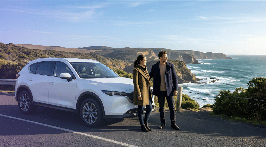 white modern intermediate SUV parked smoothly on a sealed asphalt scenic lookout point along a rugged Australian coastline