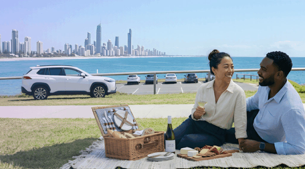 Our sophisticated urban couple enjoying a premium artisanal picnic and a stunning panoramic view of the iconic Gold Coast skyline from the Burleigh Heads headland after their successful white SUV rental from our central branch.